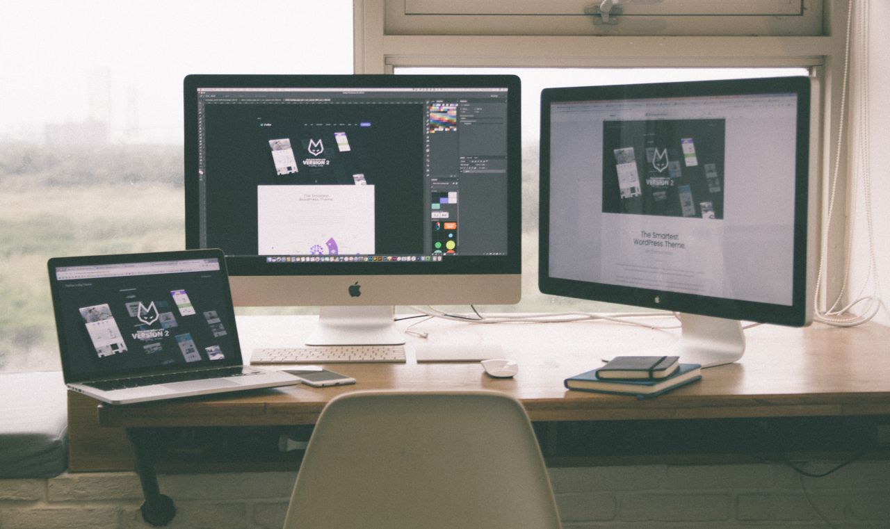 ours-journey Stylish and efficient workspace with multiple monitors, laptop, and smartphone, showcasing a web design project.